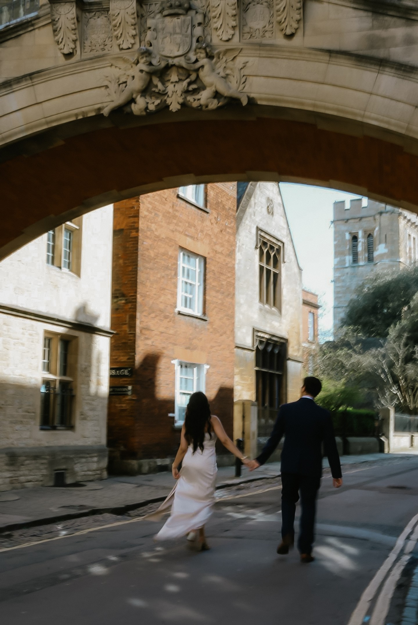 Aditya and Rubina walking hand in hand beneath a stone archway